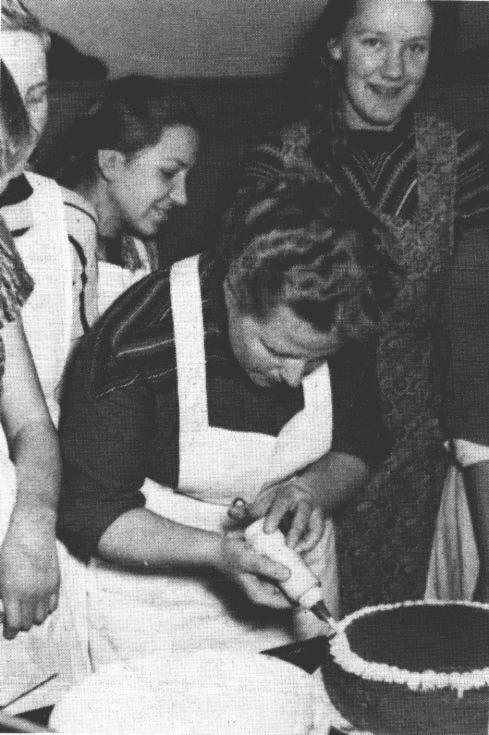 Die damalige Leiterin der EWE-Lehrkche in Leer, Frau Schobert, zeigt Anni Susan und Gisela Appeldorn, wie eine Torte fachgerecht garniert wird.