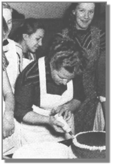 Die damalige Leiterin der EWE-Lehrküche in Leer, Frau Schobert, zeigt Anni Susan und Gisela Appeldorn, wie eine Torte fachgerecht garniert wird.